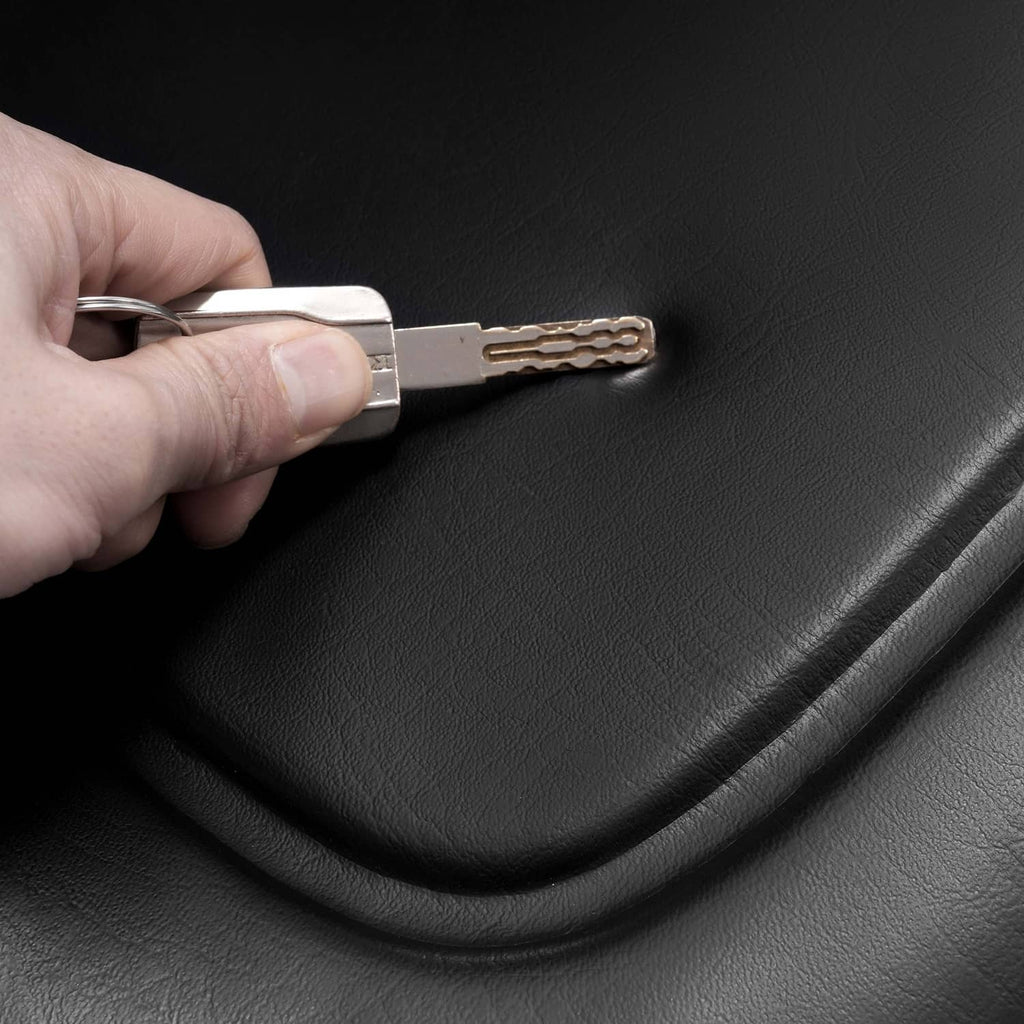 Close-up of hand holding a metal key to secure a black seat bolt area.