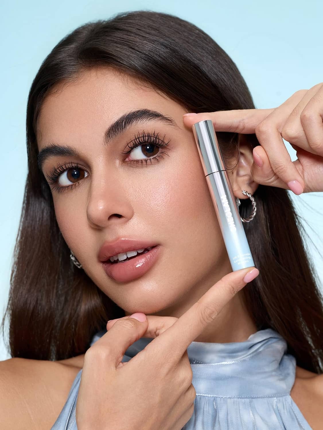 Silver mascara tube and black mascara wand near eye and lashes