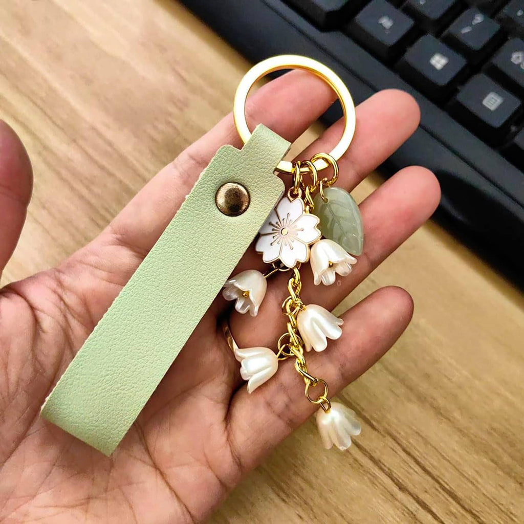 Mint green leather keychain with gold ring and white flower tassel charm dangles