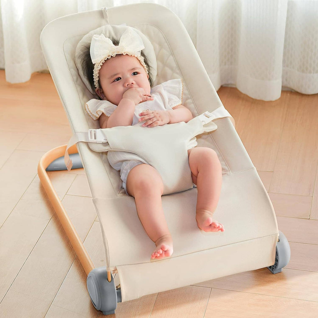 Cream baby bouncer seat with quilted cushion, infant sitting back with harness on