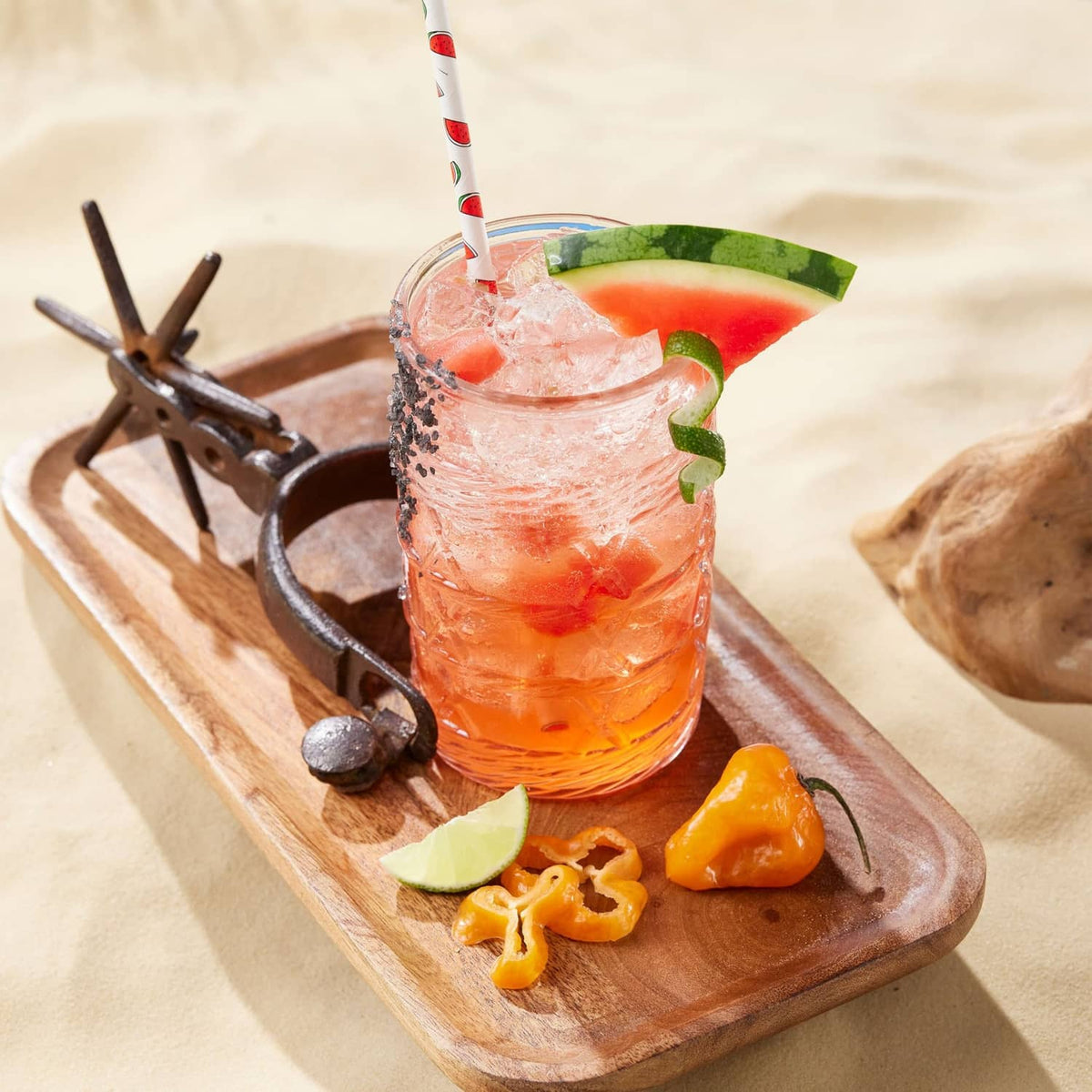 Watermelon syrup drink in tall glass with ice, lime, and watermelon garnishes