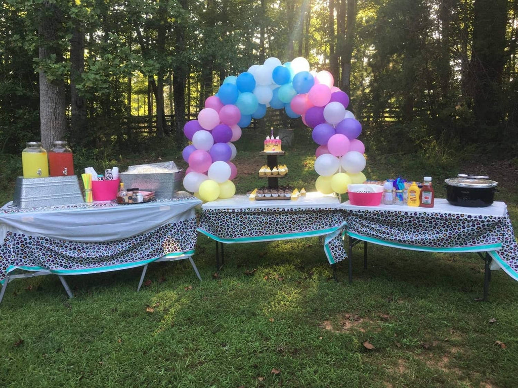Outdoor table balloon arch with pastel purple, pink, blue, and yellow balloons