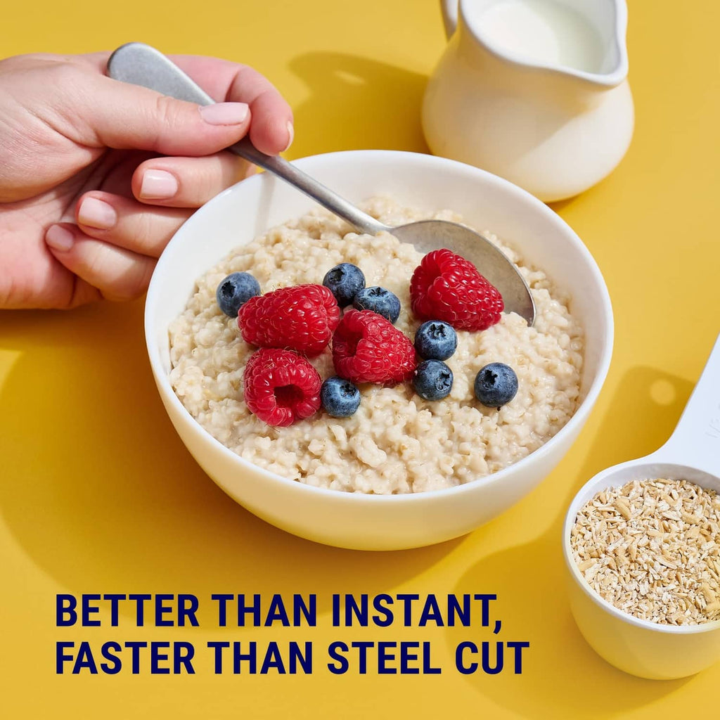 Bowl of oatmeal topped with blueberries and raspberries with spoon and milk pitcher