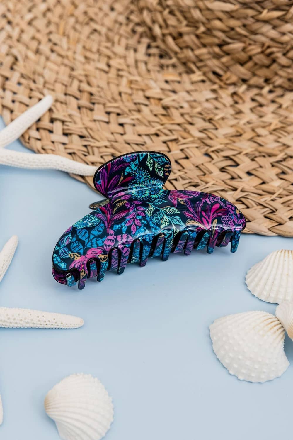 Colorful floral claw hair clip with clear hinge and gold spring, curved black teeth.