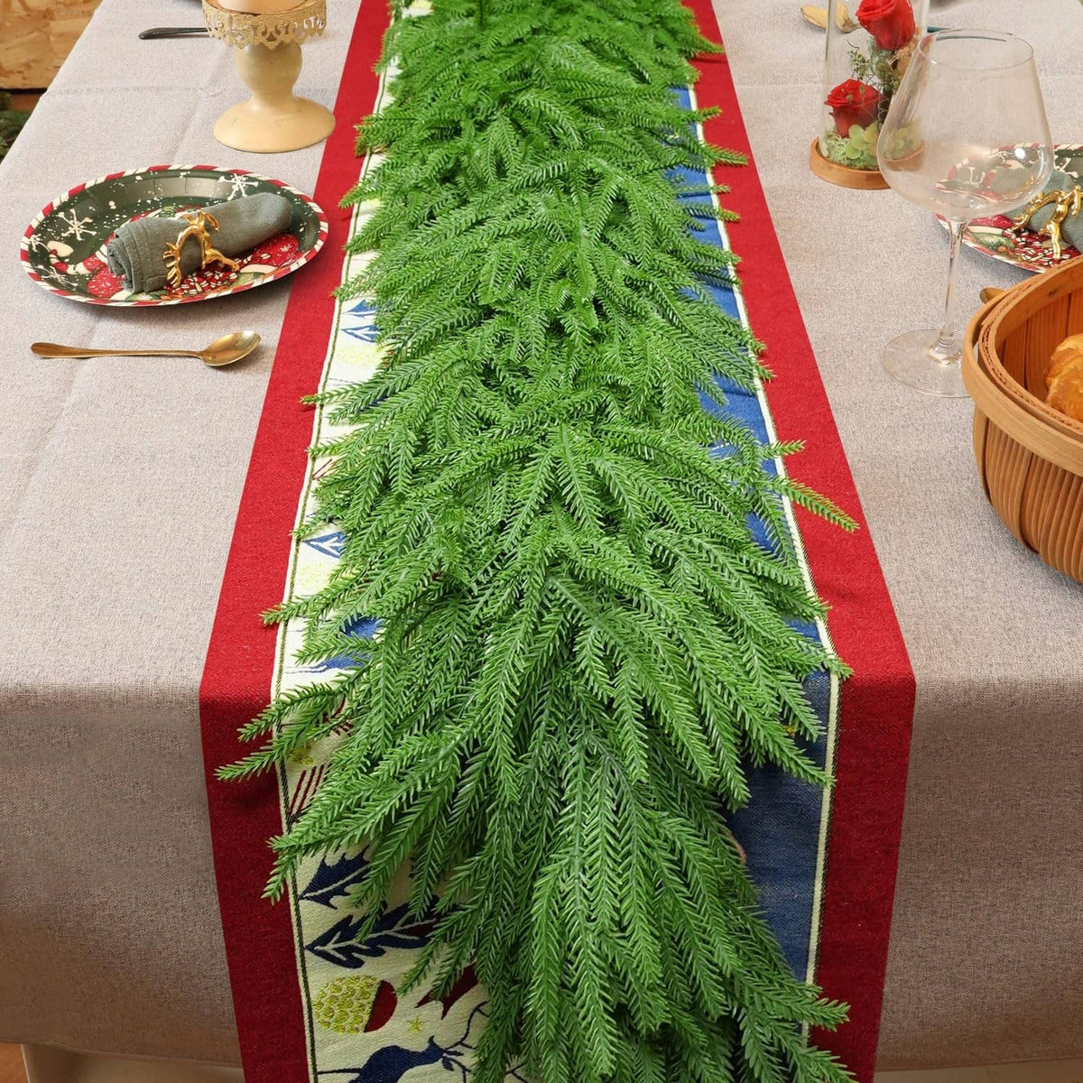 Green artificial pine garland with layered needle branches, decorated with small blue accents.
