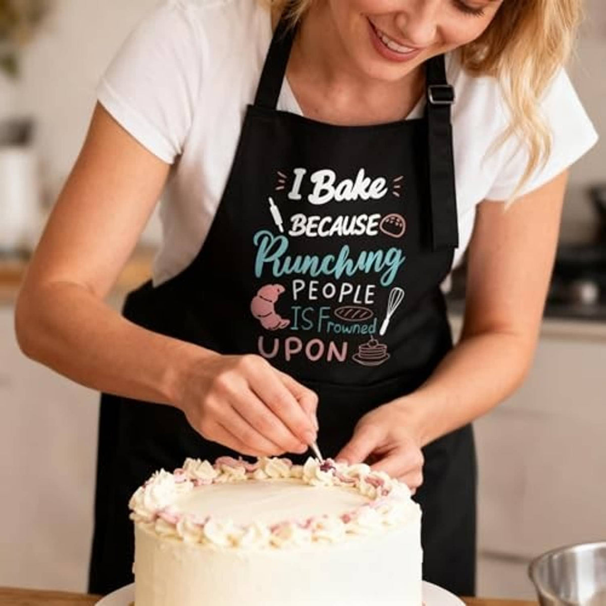 Black I Bake apron worn by person, colorful 'Punching People' print with front pocket