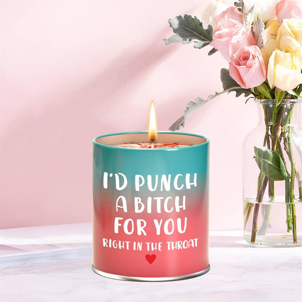 Scented teal-and-pink candle with flame and white text, beside pink roses bouquet
