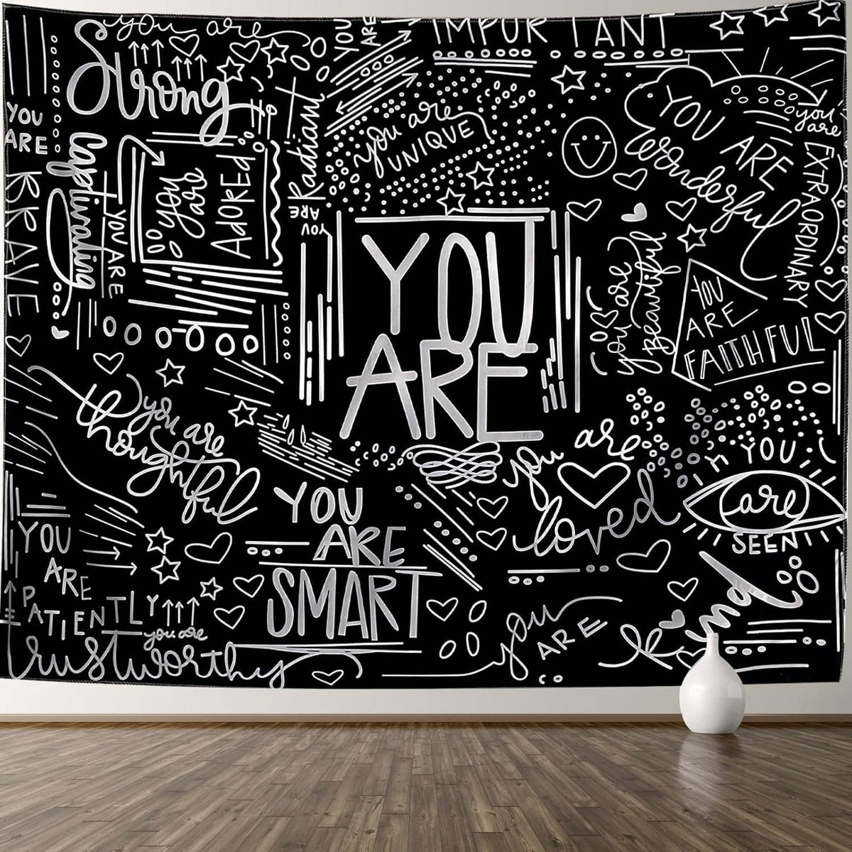 Black and white motivational tapestry on wall with chalk-style script and hearts