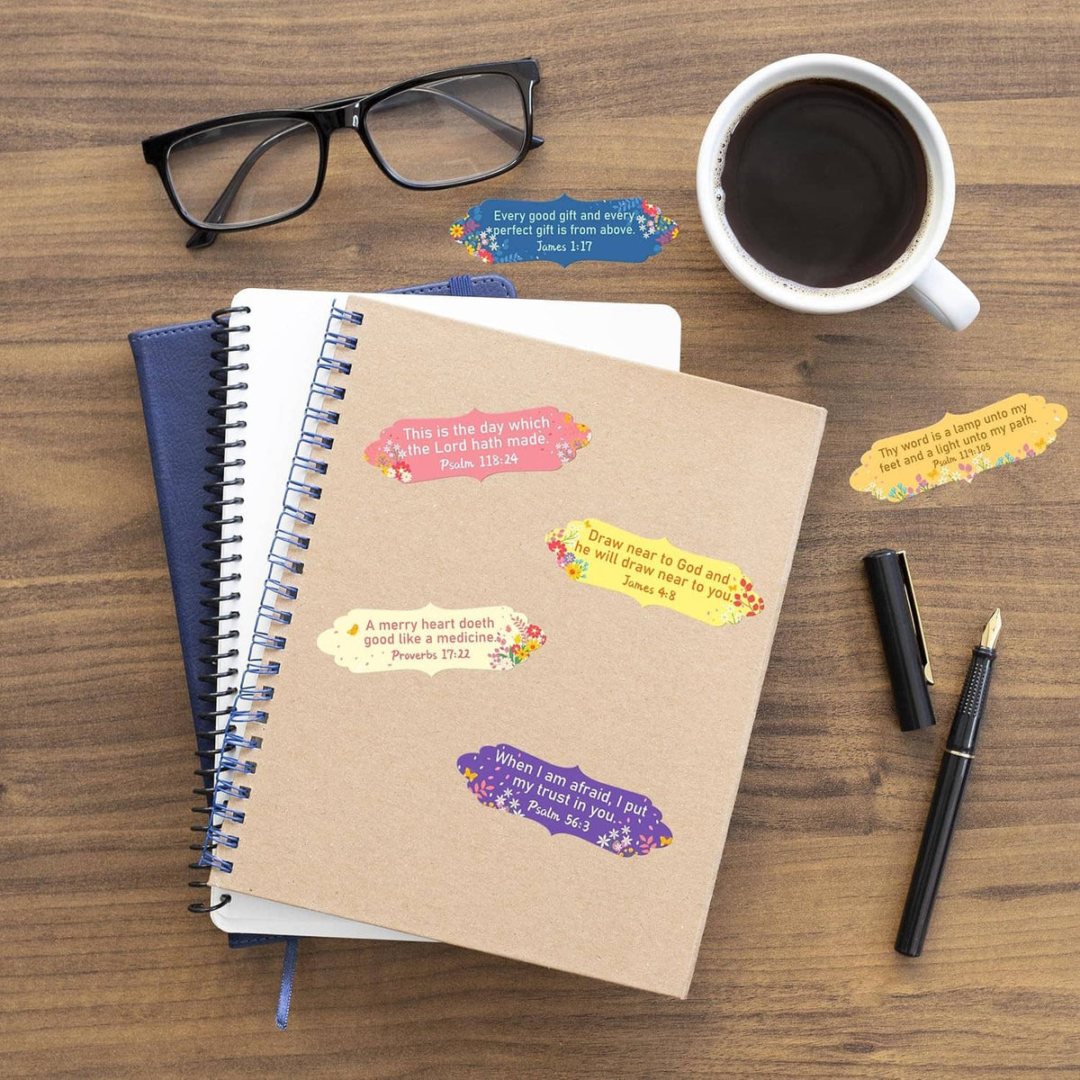 Bible verse stickers adhered to kraft notebook cover, with scattered labels nearby