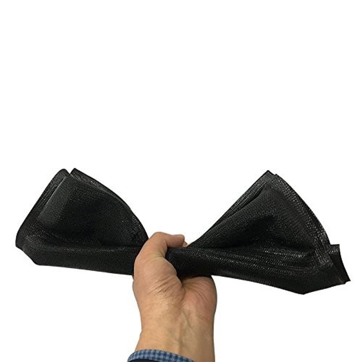 Black flexible silicone hot dog mold, folded and held in a hand