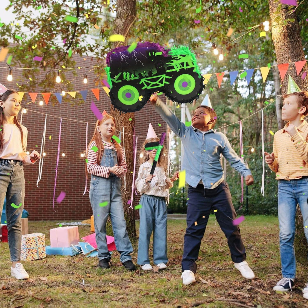 Monster truck piñata with green and purple design, held up at a kids' party