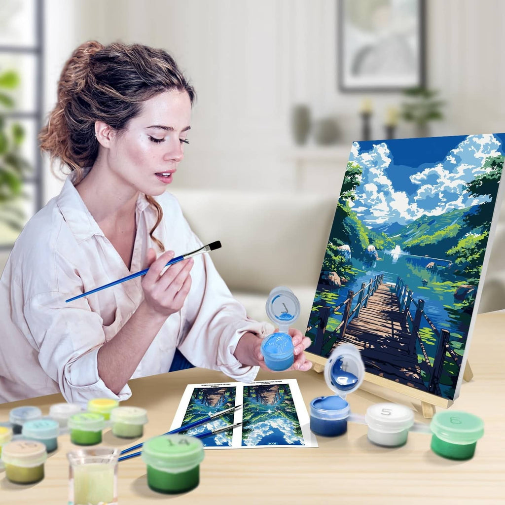 Adult painting a lakeside landscape on a paint-by-numbers canvas