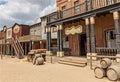 Western scenic photo backdrop with rustic buildings, barrels, and dusty street