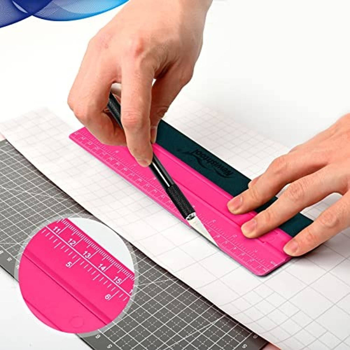 Hands using rose pink vinyl squeegee with dark blade on grid cutting mat