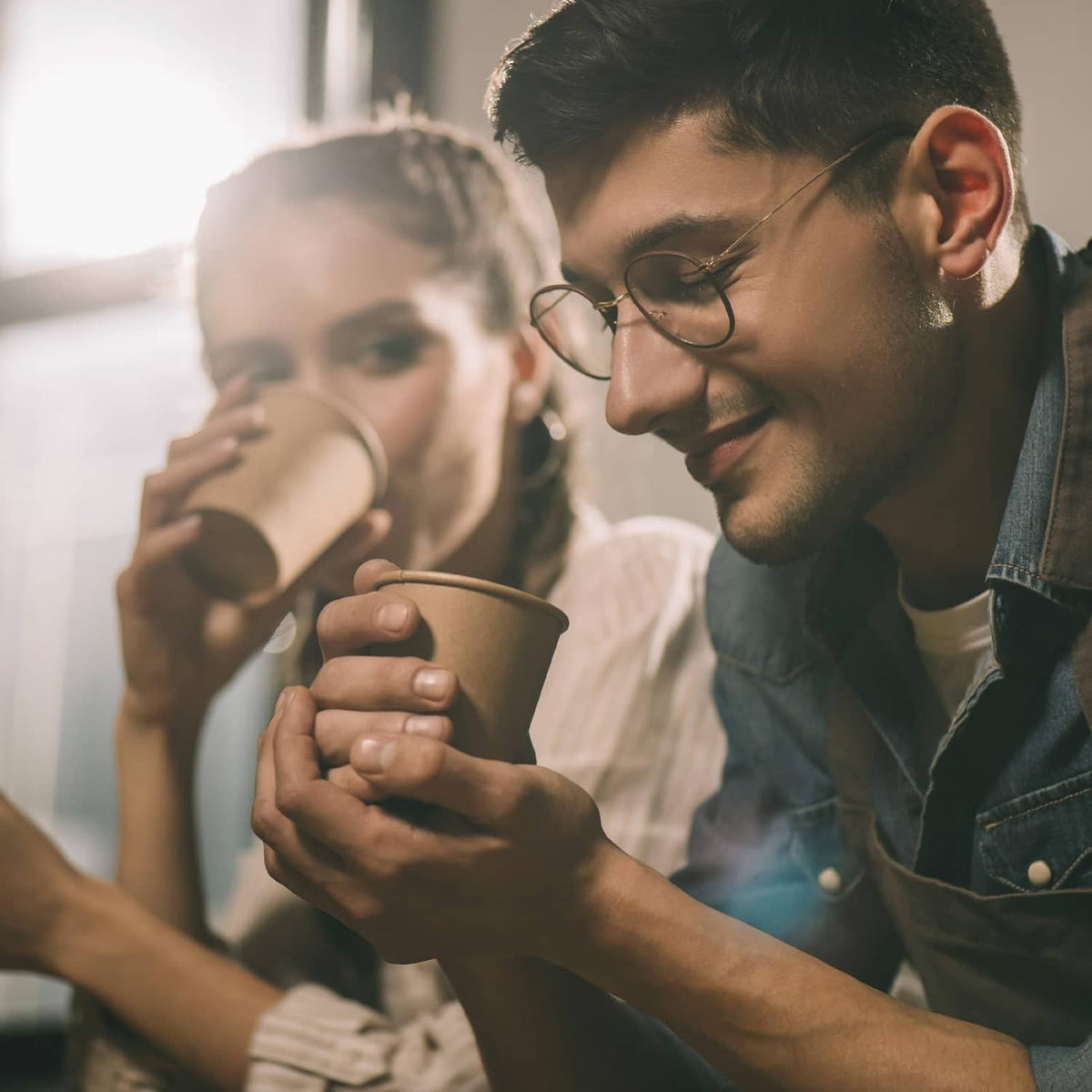 Brown kraft paper cups in people’s hands for hot drinks