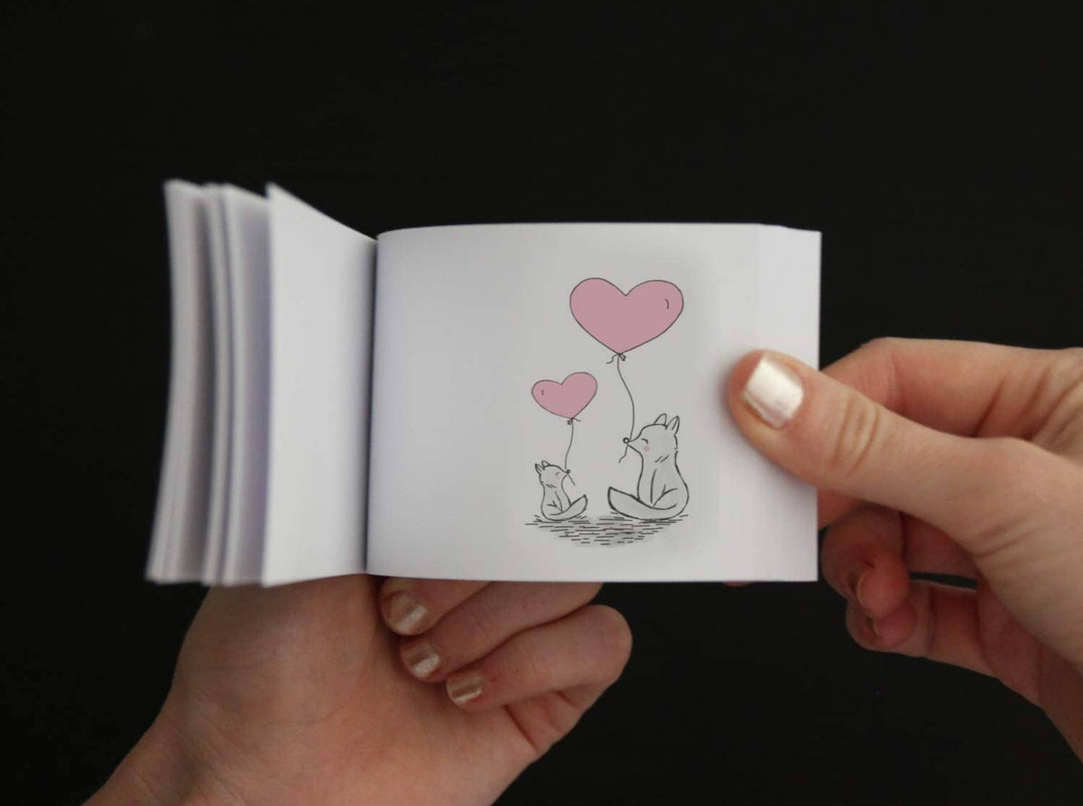 Blank flip book pages with small illustrated drawing, held open by hands