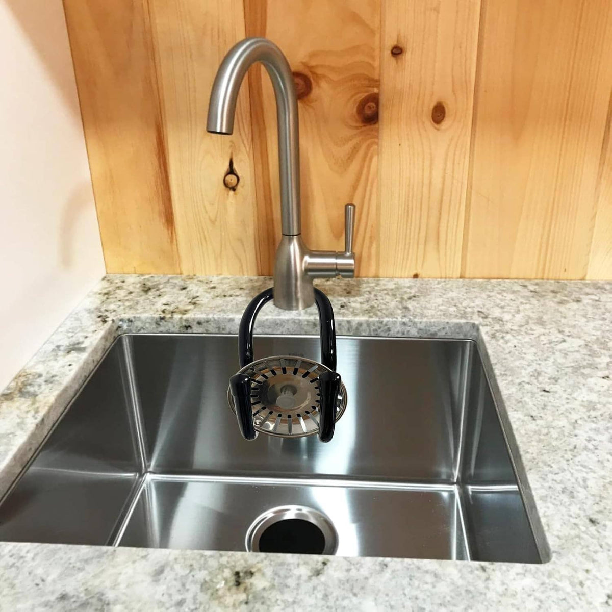 Hanging sink caddy with black hooks and wooden-handled scrubbing brush