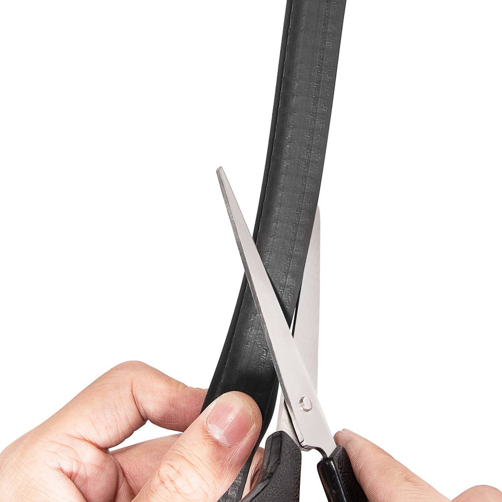 Hand cutting black rubber door weatherstrip seal with scissors