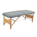 Gray portable massage table with padded two-section top and wooden folding frame