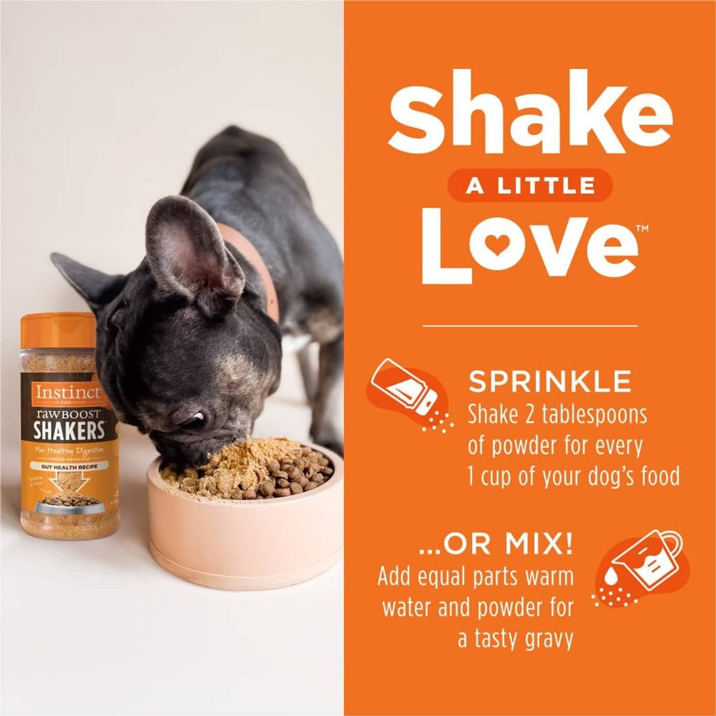 Cat beside a bowl of freeze-dried dog food and an orange-lidded shaker container.