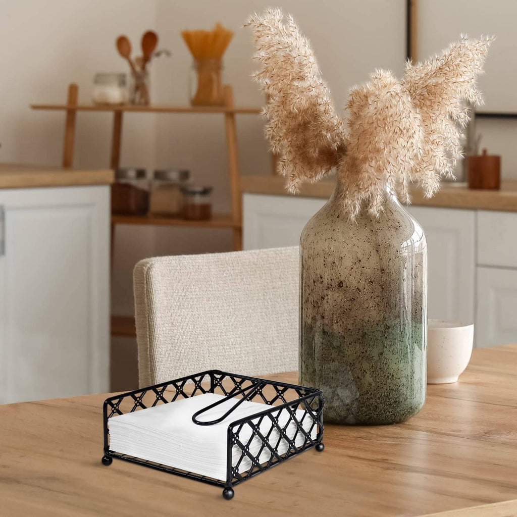 Black lattice napkin holder with folded white napkins and curved handle on table.