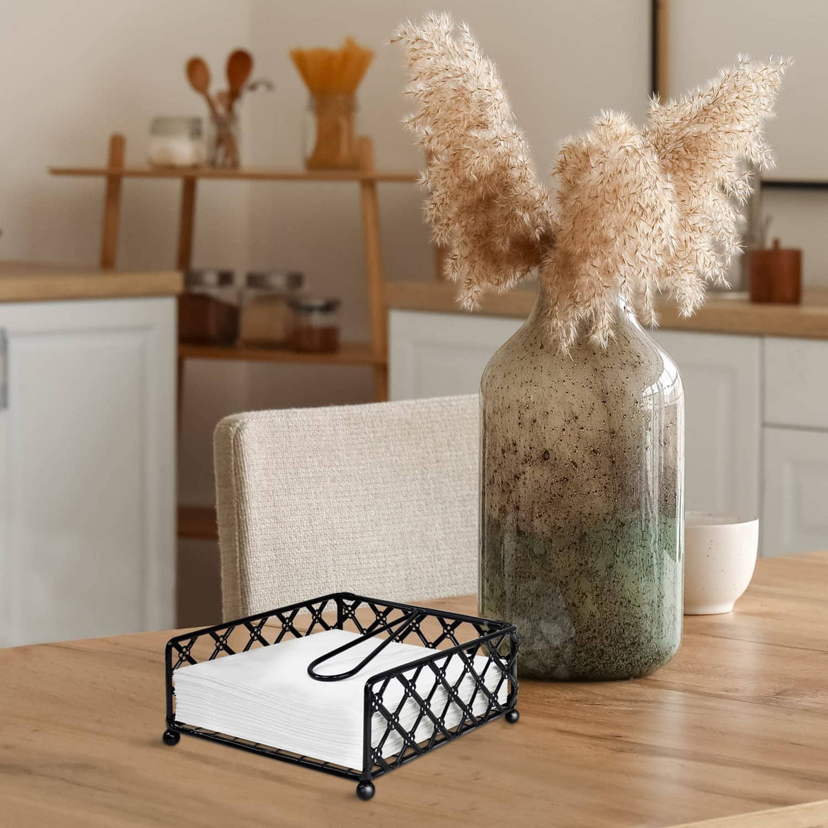 Black lattice napkin holder with folded white napkins and curved handle on table.
