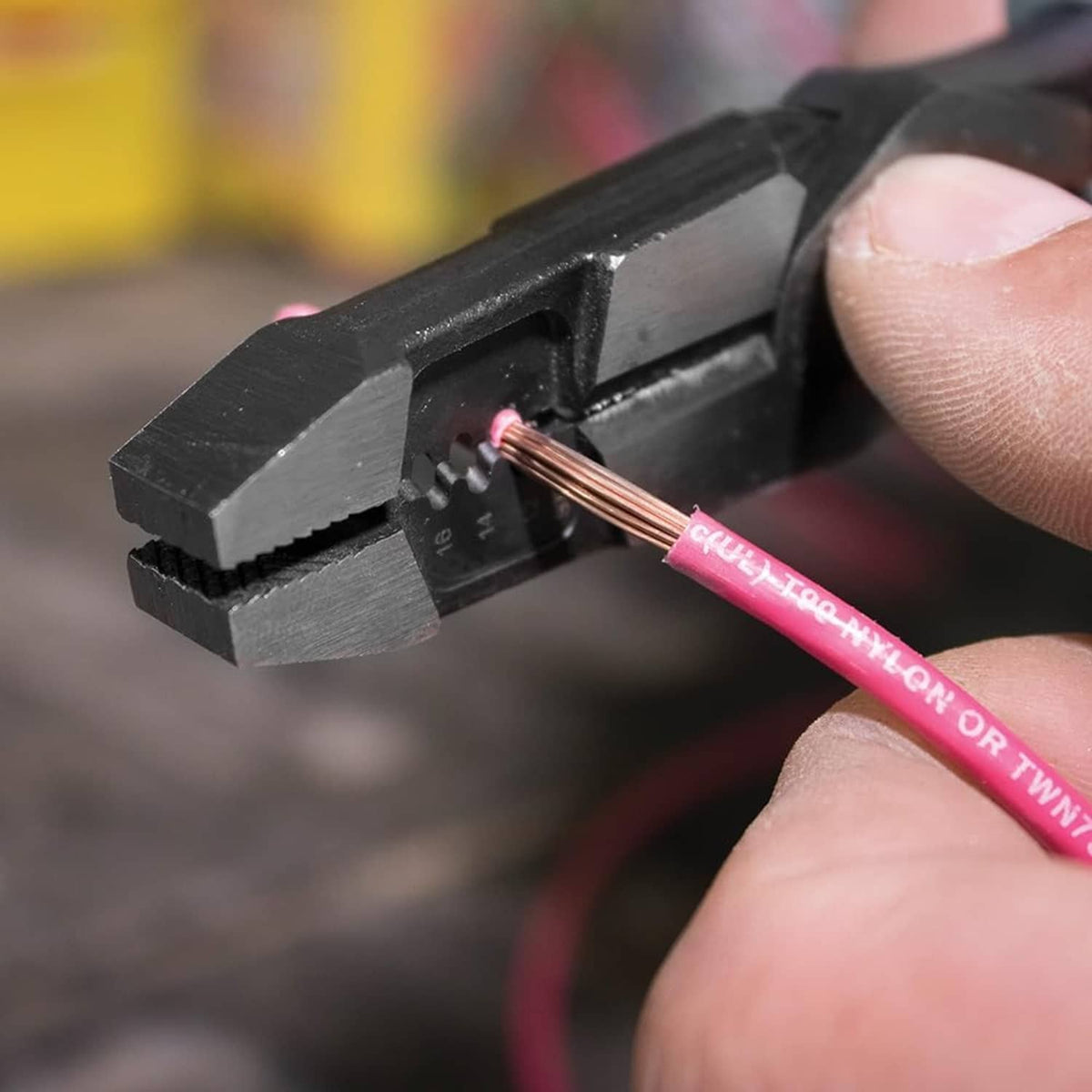 Hybrid multitool pliers cutting a stripped wire end with copper and pink insulation