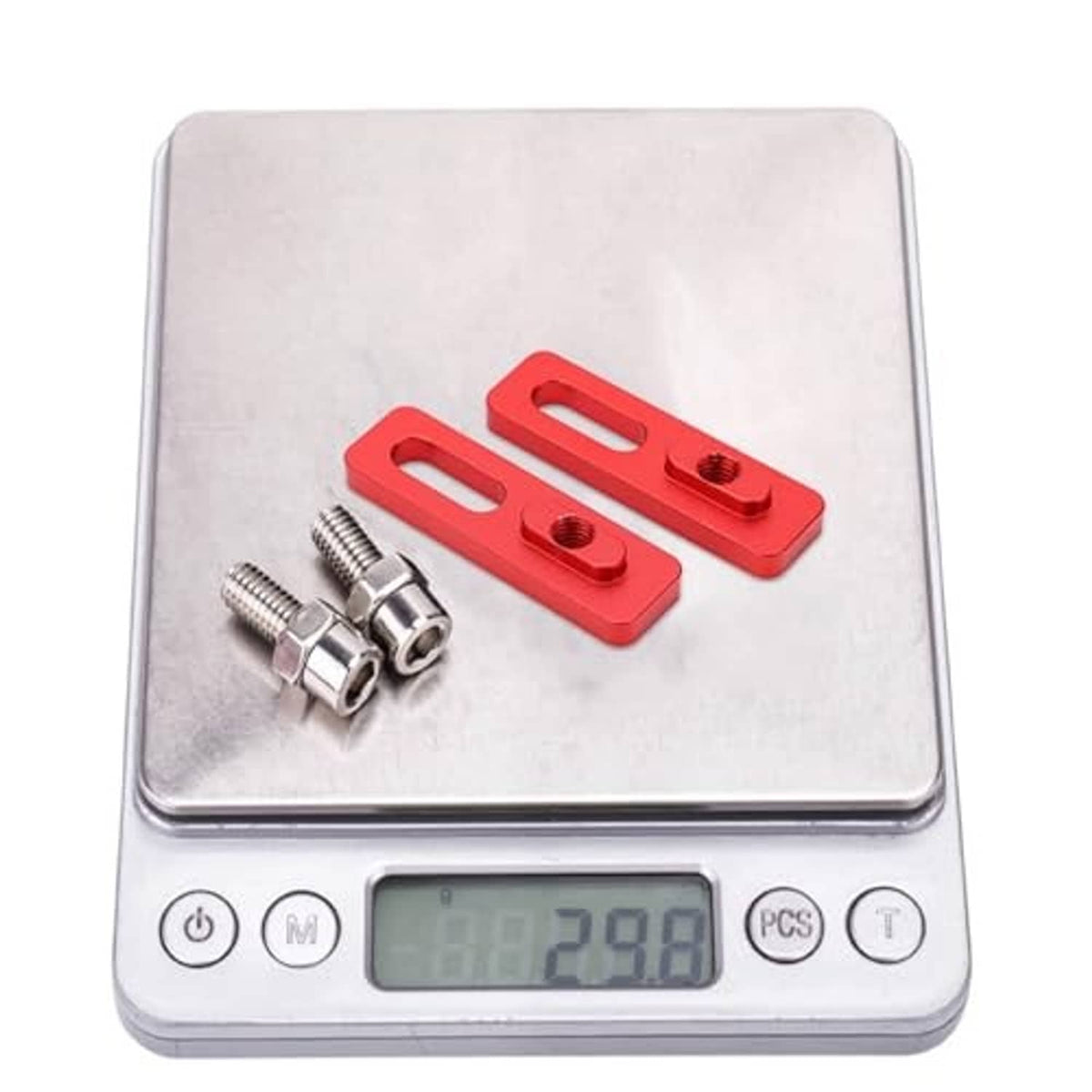 Red V-brake extension converter plates and silver mounting bolts on a digital scale
