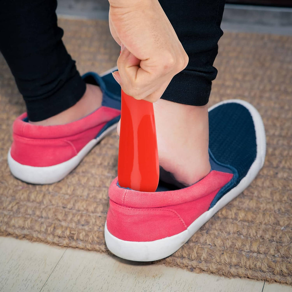 Red plastic shoe horn guiding a foot into a red canvas sneaker