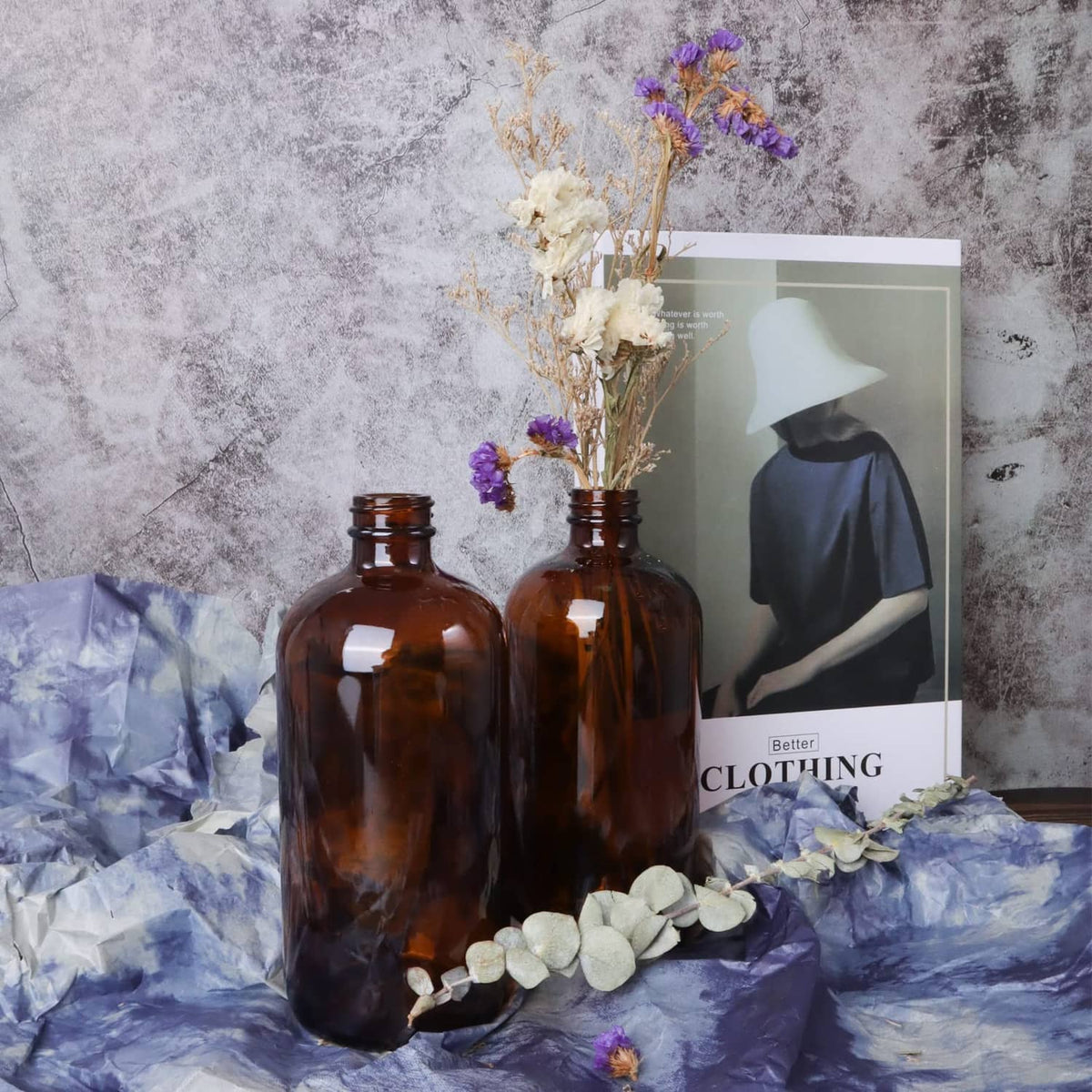 Amber glass bottles with black caps on paper flowers arrangement with a book.