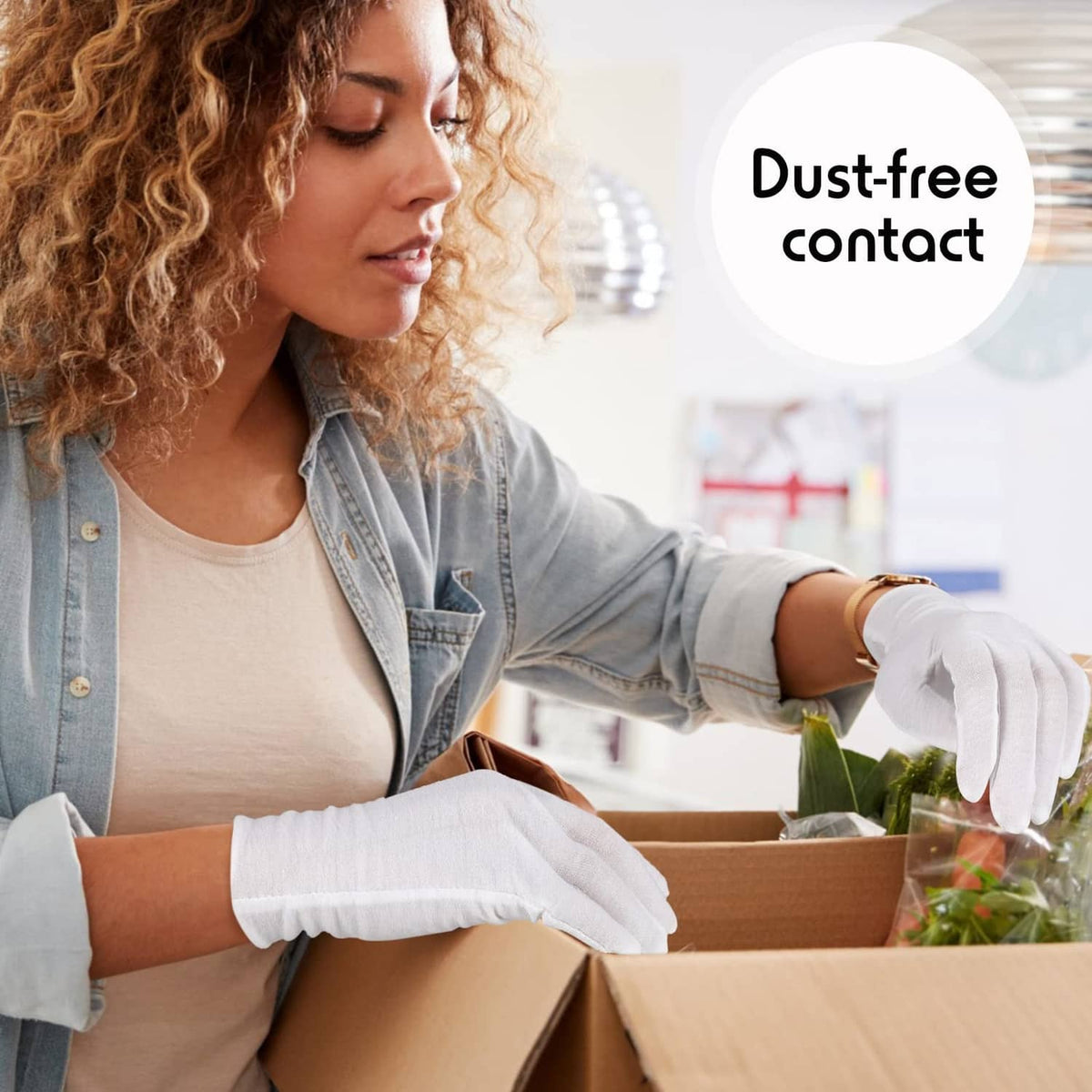 White cotton gloves on hands while packing items in a cardboard box