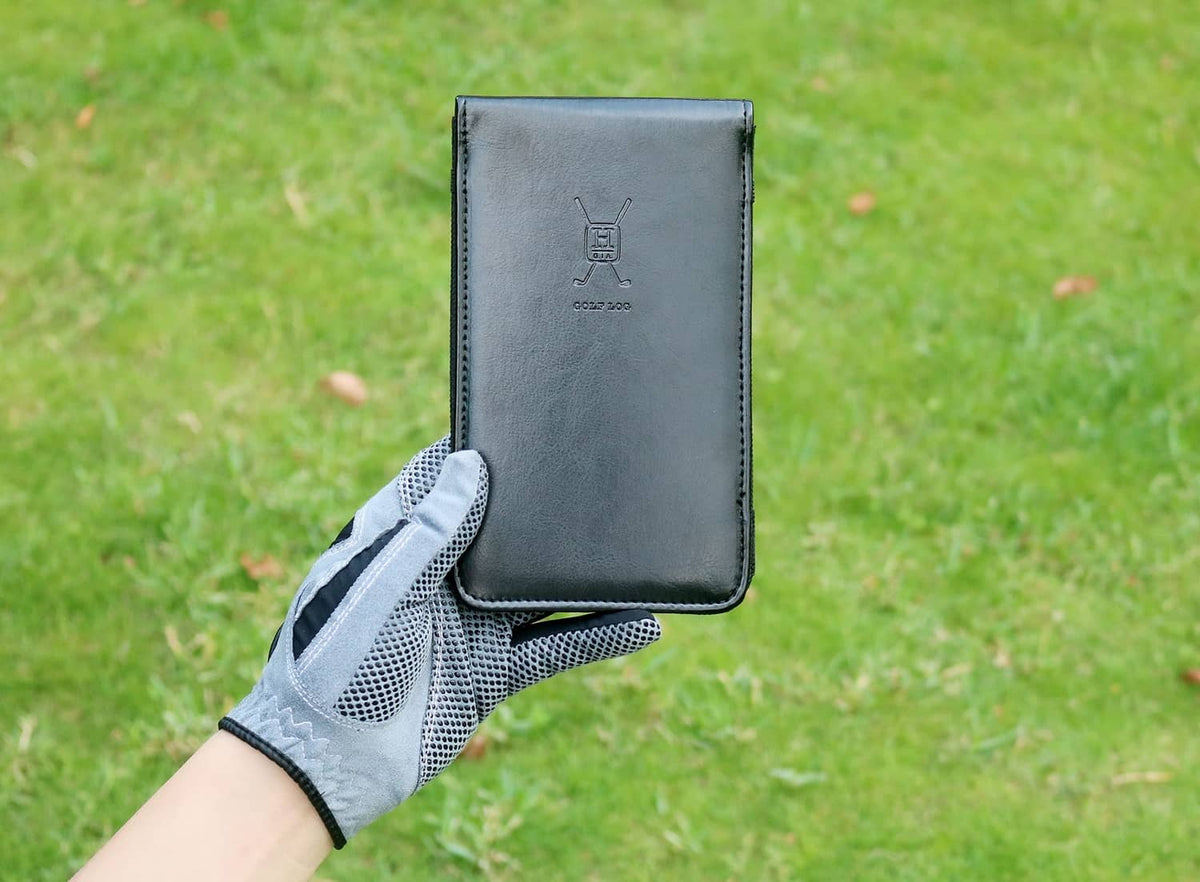 Black leather golf scorecard holder in hand, stitched edges and scorecard logo