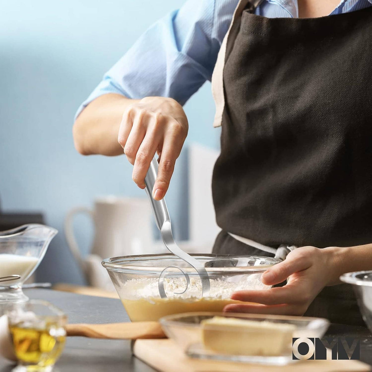Stainless steel dough whisk stirring batter in a glass mixing bowl