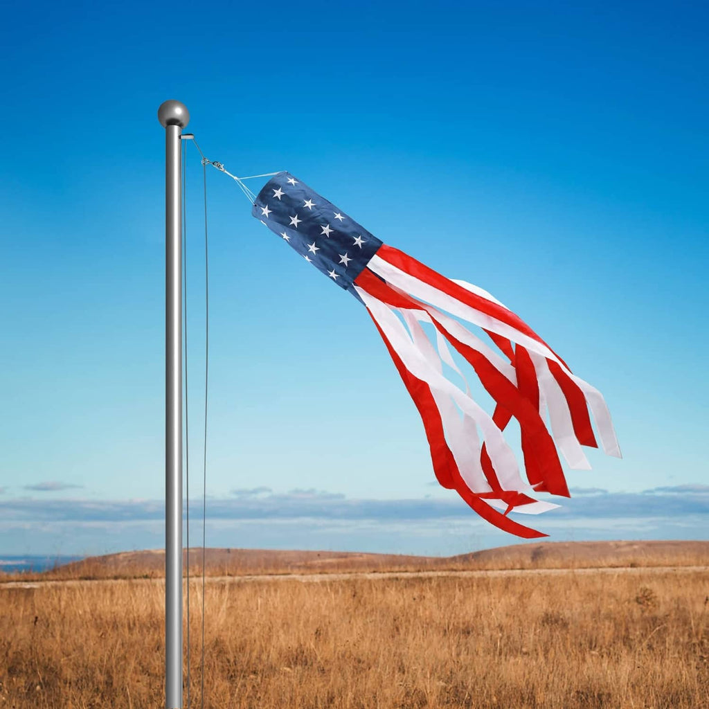 US flag windsock on a tall pole waving over an open field