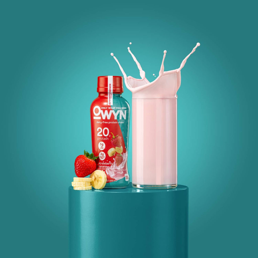 OWYN strawberry banana protein shake bottle with glass of pink shake and splash