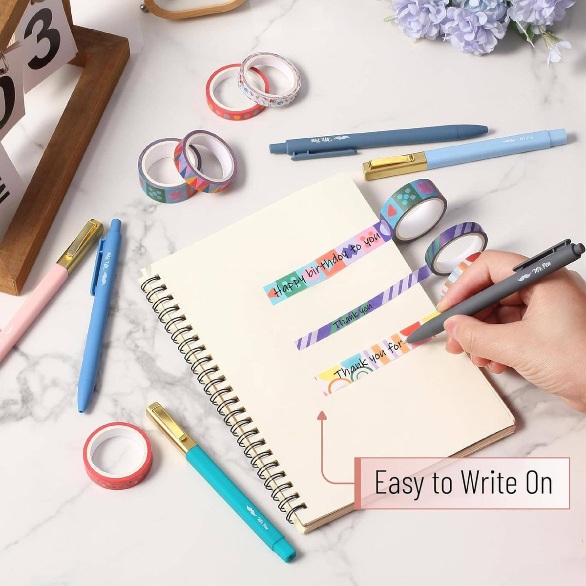Colorful washi tape strips and rolls on notebook while writing and decorating