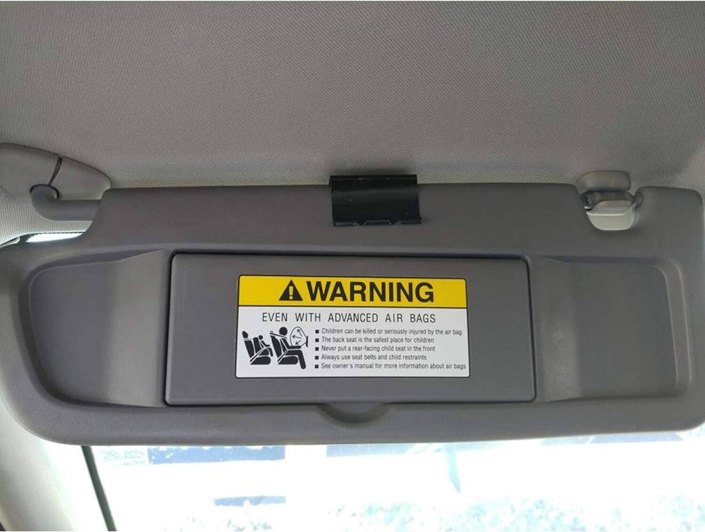 Close-up of dark gray car sun visor warning label centered on the panel