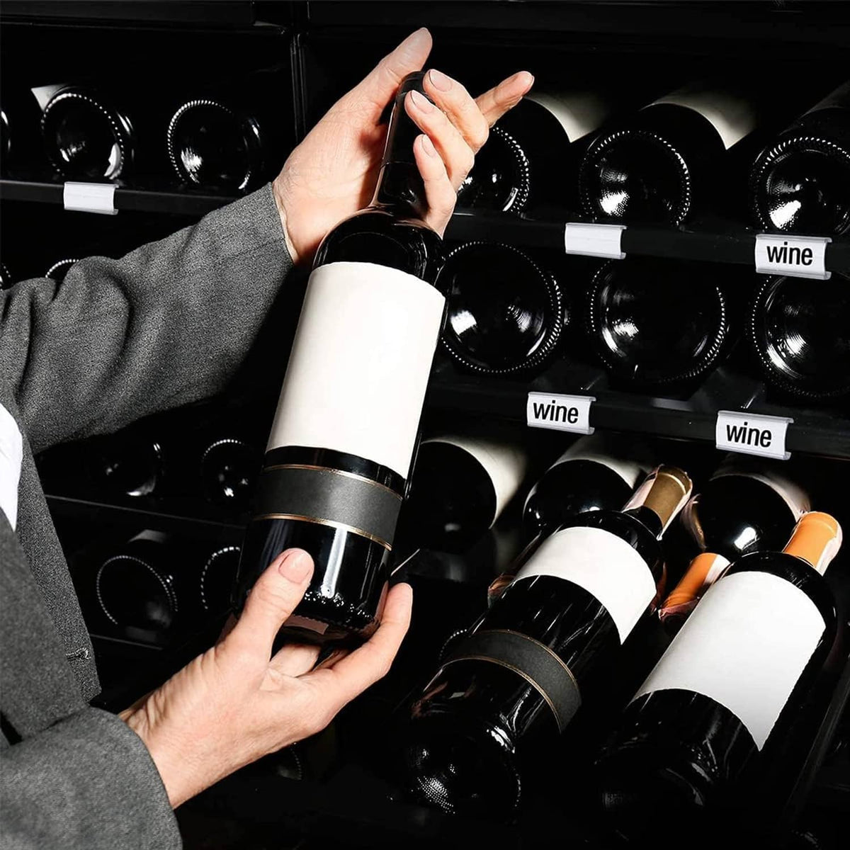 Clear shelf label holders with “wine” label cards on a bottle display rack