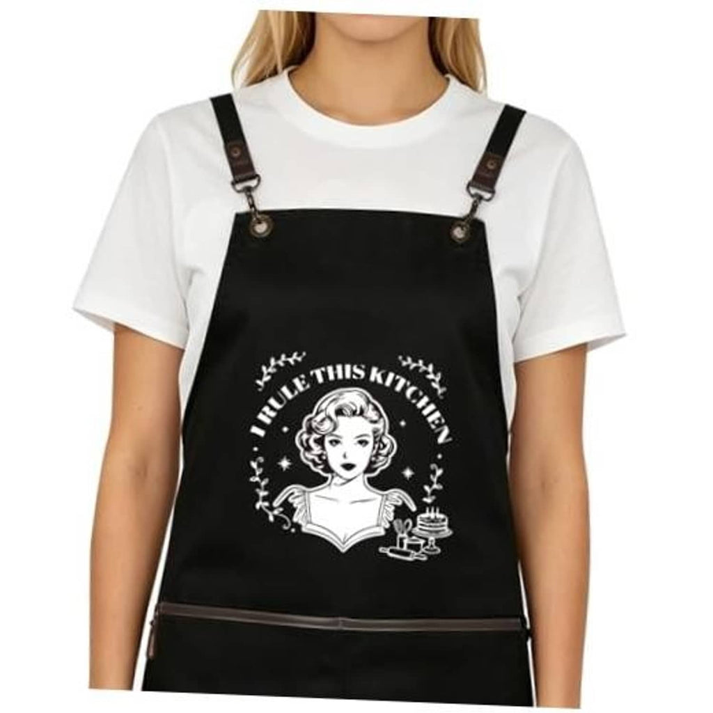 Black cross-back apron with chef-style graphic and adjustable leather buckles