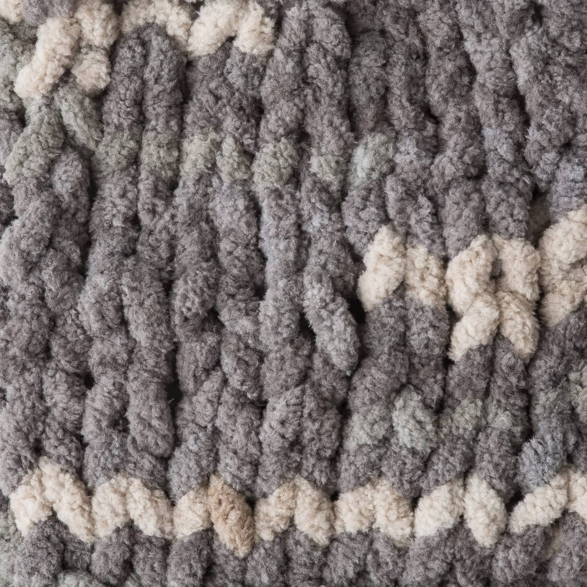 Close-up of super bulky chenille knit texture in gray and light cream stripes