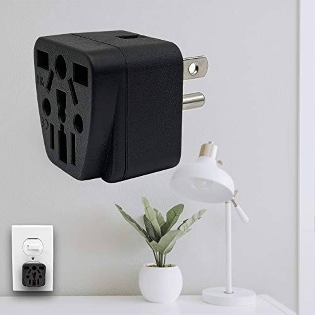 Black travel plug adapter mounted on wall with two metal prongs and socket holes