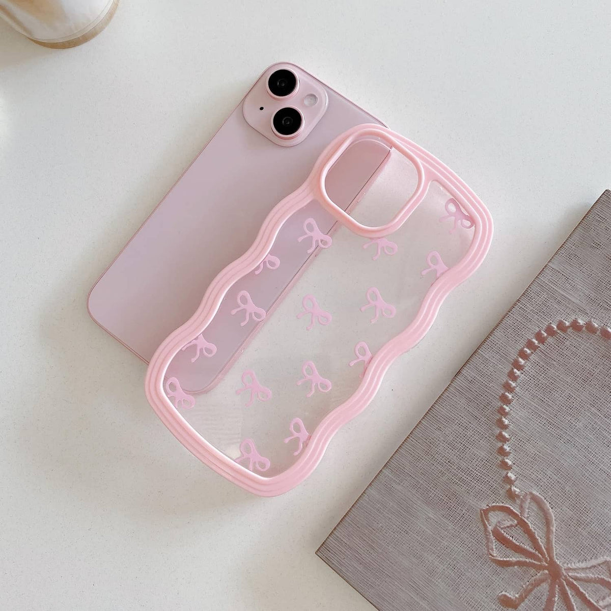 Pink clear phone case with bow pattern, glossy raised border, and camera openings.