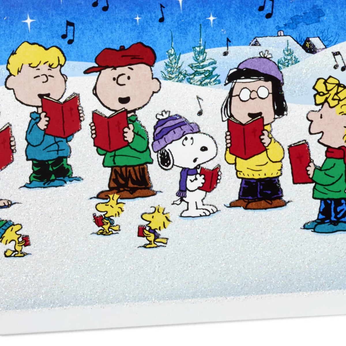 Close-up holiday card illustration of Peanuts characters caroling with snow and music notes
