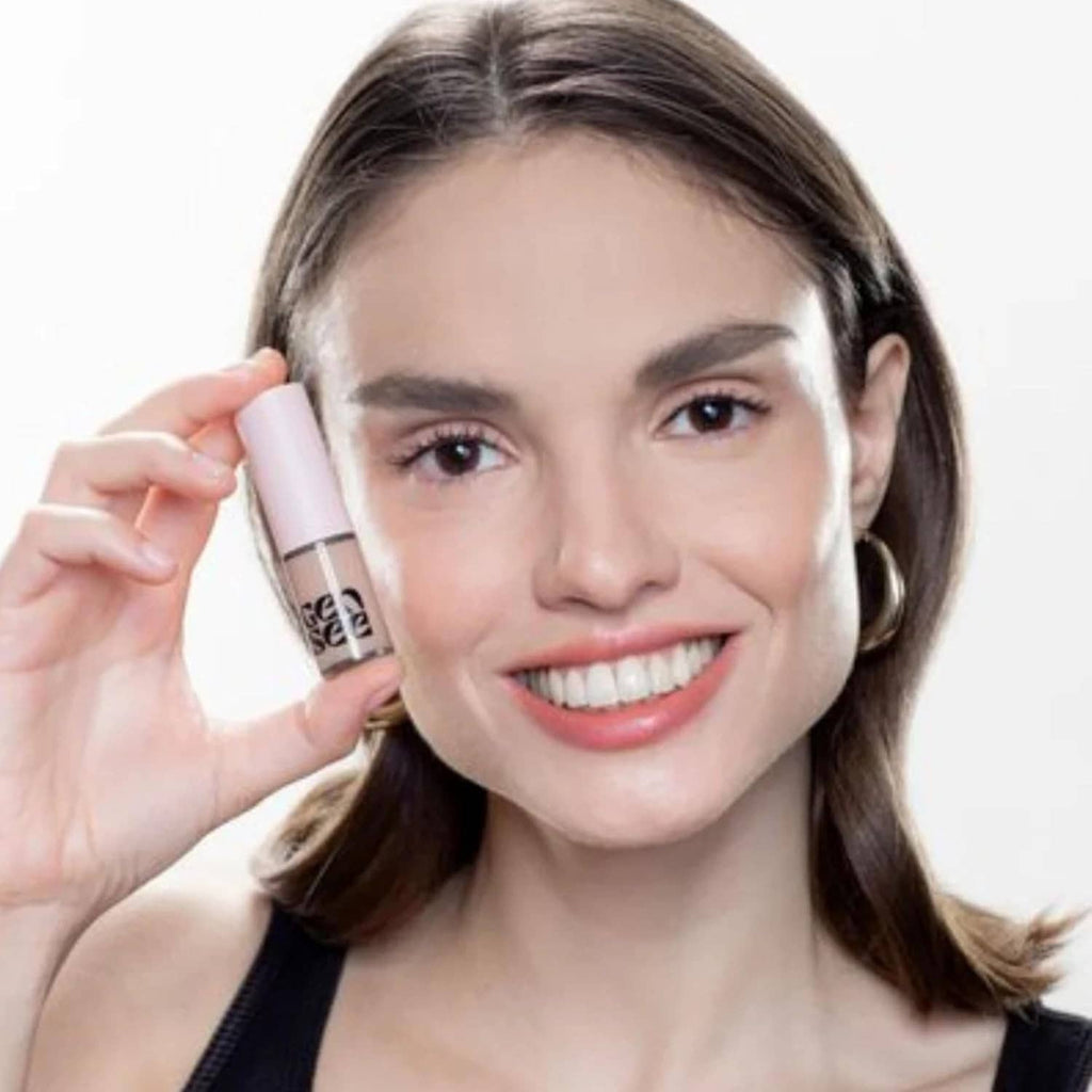 Woman holding pink liquid eyeshadow tube near face, rose shimmer eyeshadow look