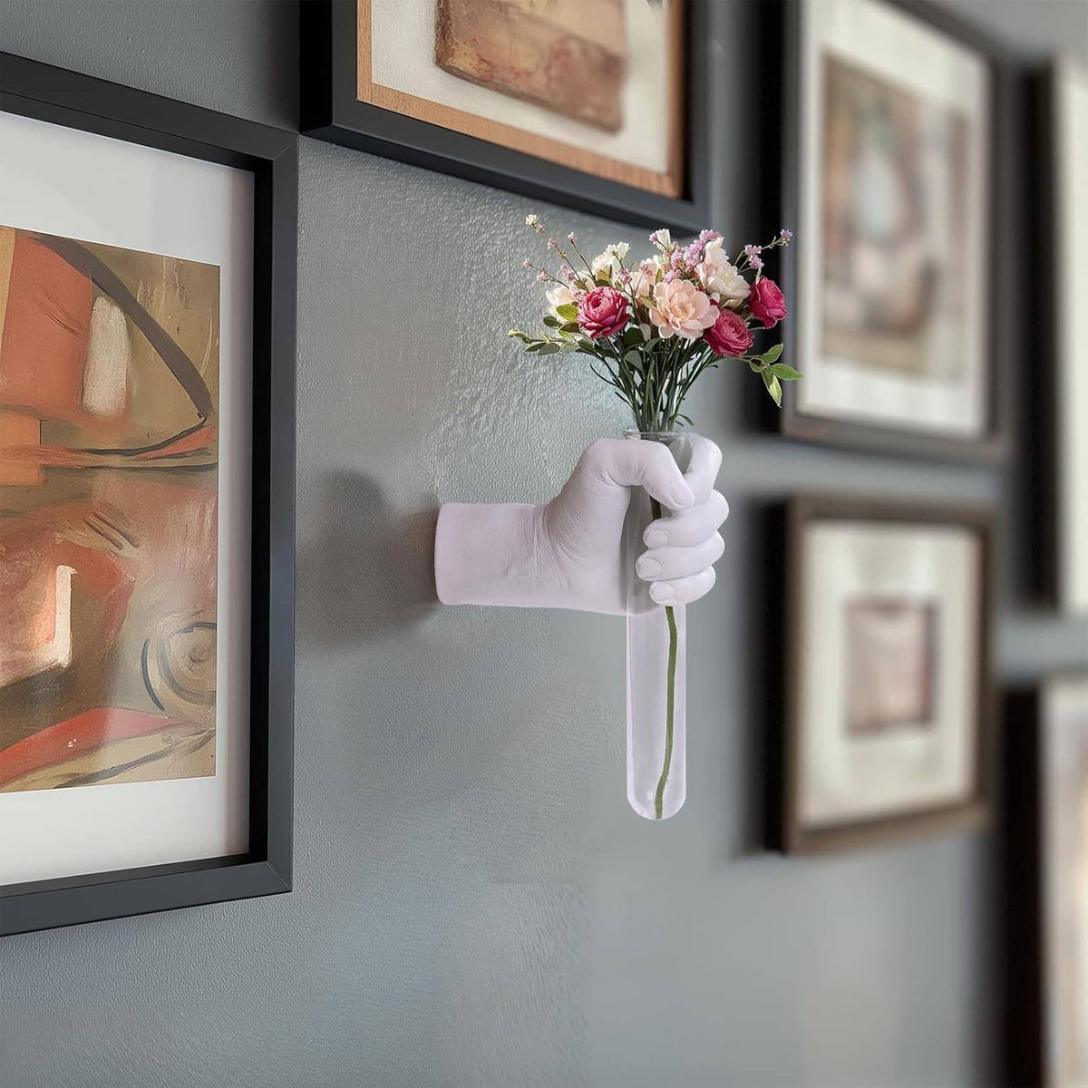 White hand vase wall hanging holding a bouquet of pink flowers