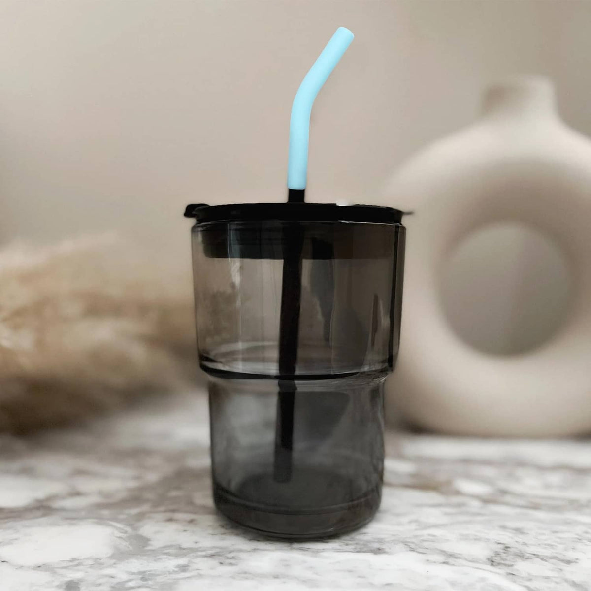Light blue silicone straw elbow tip on a straw in a dark cup