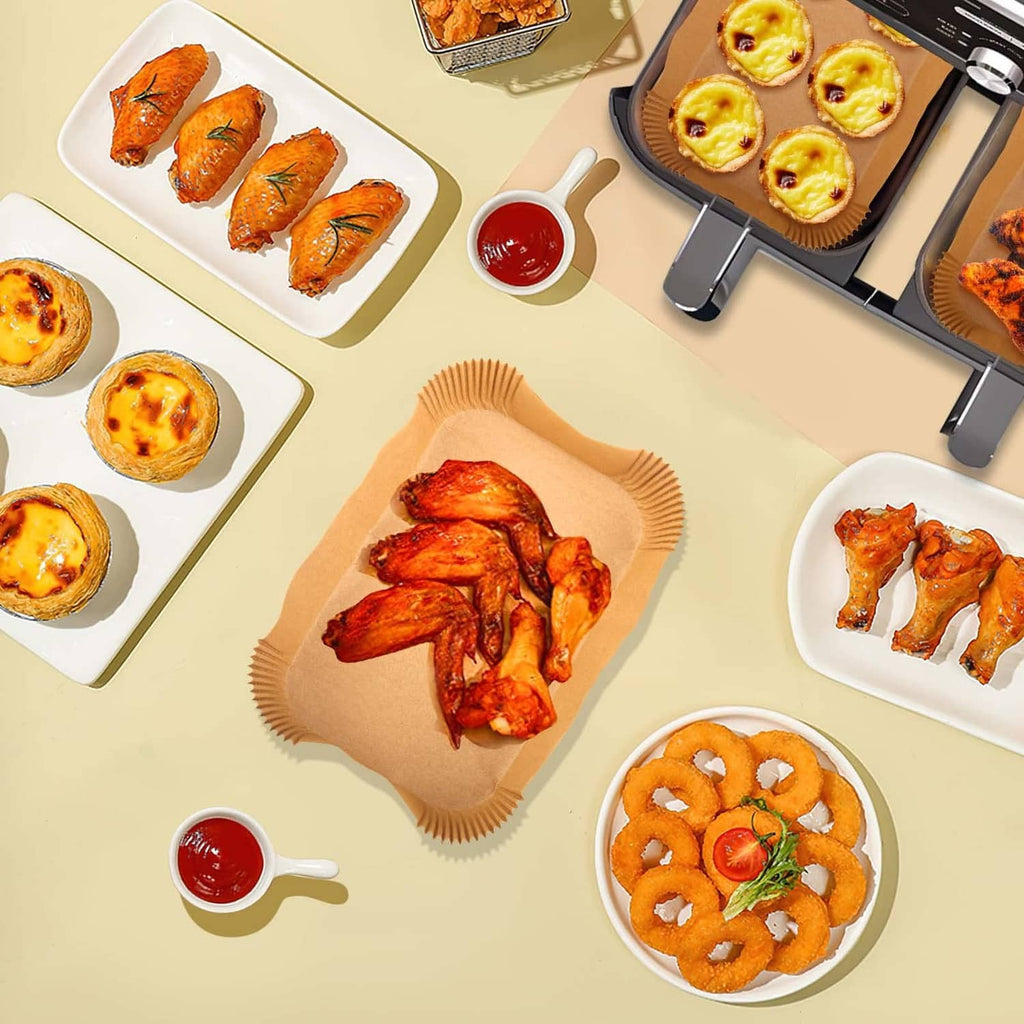 Rectangular air fryer baking paper liners with cooked foods arranged for serving