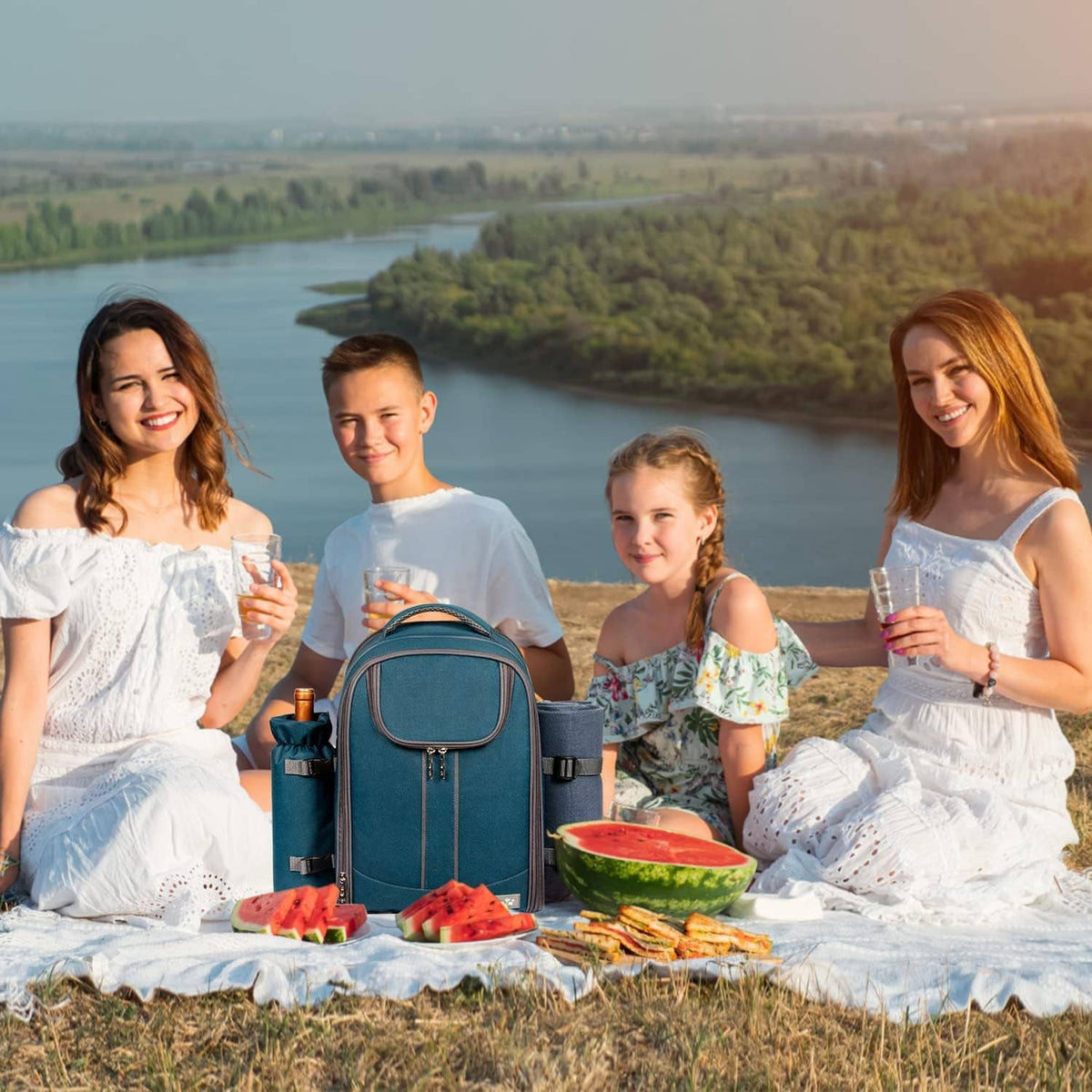 Teal picnic backpack on a blanket during outdoor meal, with front partially open