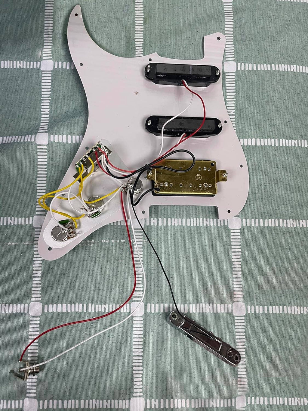Black pickguard underside with wiring harness, pots, and pickup connection terminals
