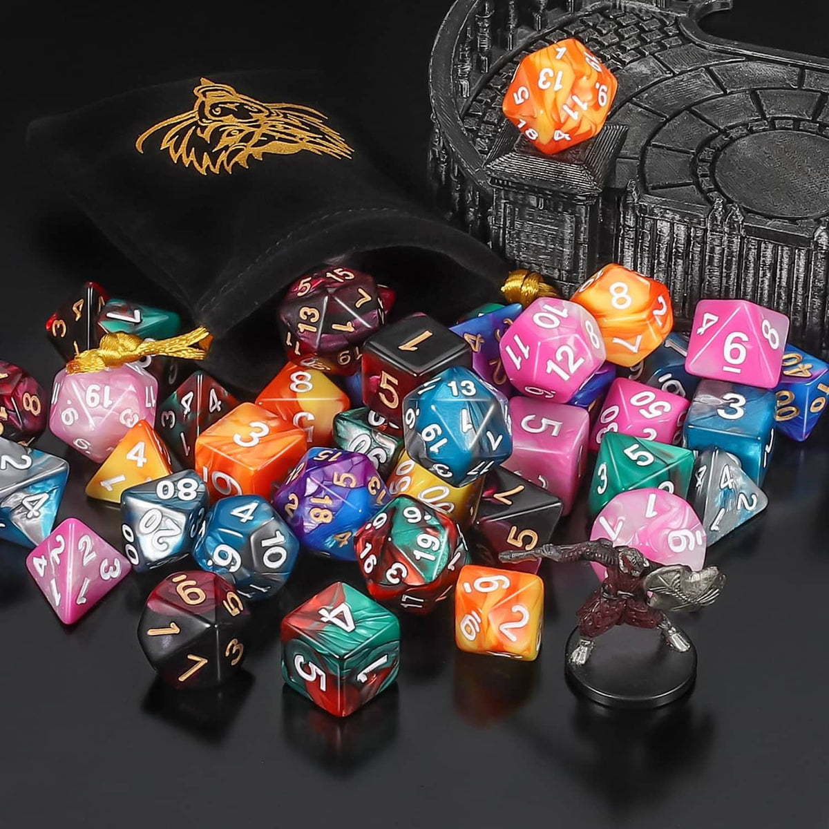 Polyhedral dice clustered near a dragon-emblem pouch; multicolor numbered dice visible